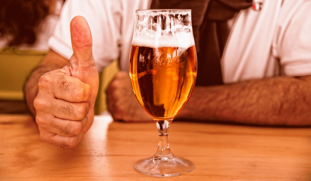 Consumidor de cerveja com uma taça num bar