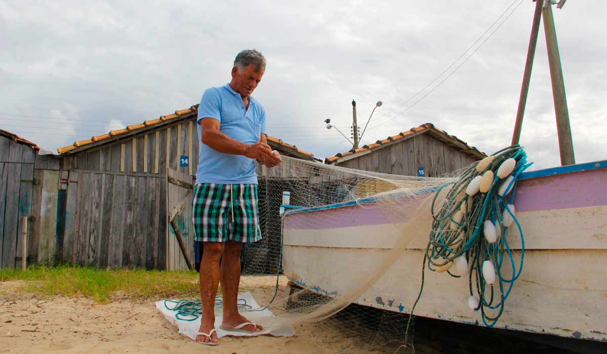 Pescador no seu rancho trabalhando com a rede